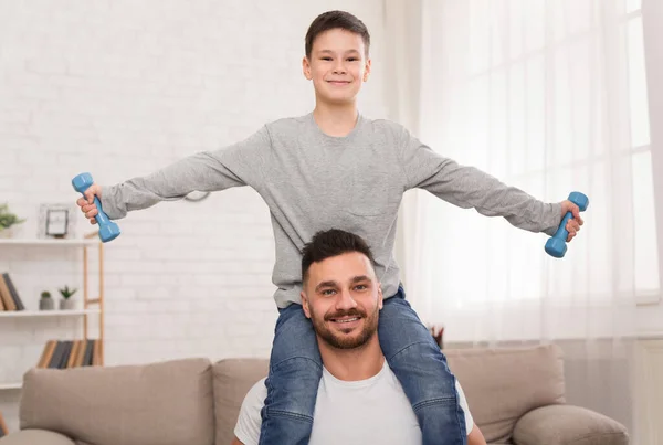 Buon padre e figlio che si esercitano con i manubri a casa — Foto Stock