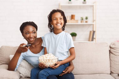 Siyah aile patlamış mısır yiyor ve birlikte televizyon izliyorlar.