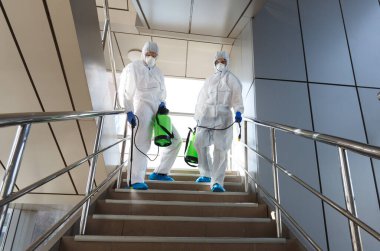 Virüs korumalı giysiler giyen adamlar variller, patojen solunum cihazları taşıyorlar.