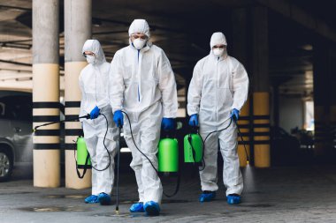 Workers in coronavirus suits cleaning streets with chemicals clipart