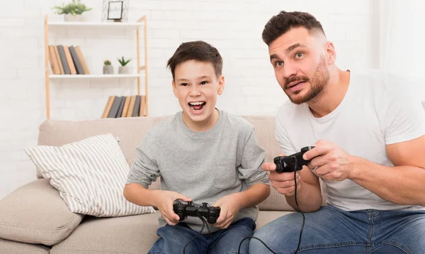 Emocional pai e filho competindo no gamepad em casa — Fotografia de Stock