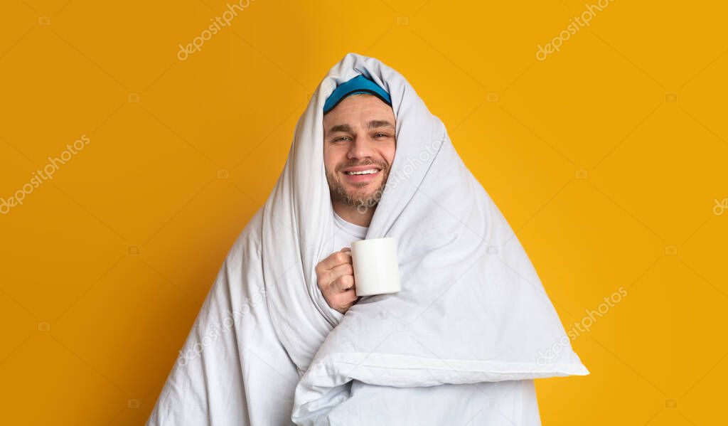 Smiling guy in blanket is holding cup