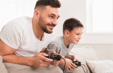 Evde video oyunu oynayan yalnız bir baba ve oğul.
