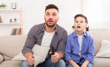 Baba oğul evde televizyon seyrediyor, boş alan.