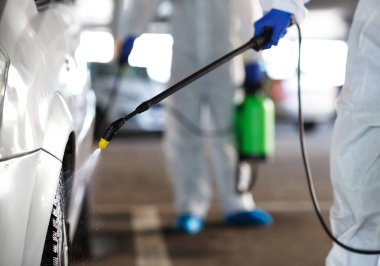 Tanınmayan işçiler arabayı kimyasallarla yıkıyorlar.