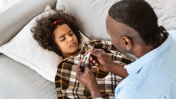 Epidemia mundial. Abuelo afroamericano cuidando de su pequeña nieta enferma en casa —  Fotos de Stock