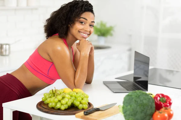 Black girl using laptop searching recipes looking at camera — Stock Photo, Image