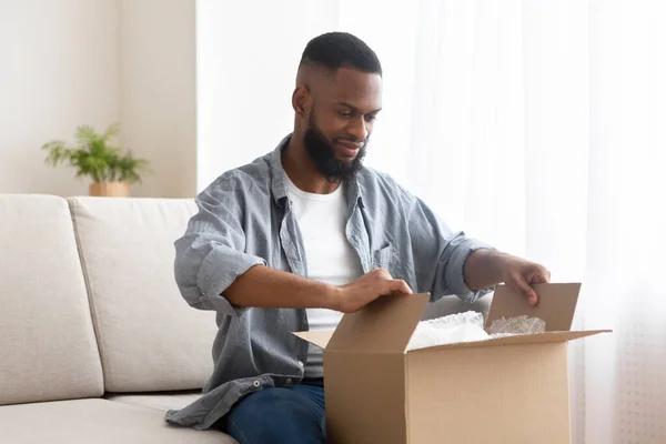 Comprador masculino descompactar caixa de papelão em casa — Fotografia de Stock