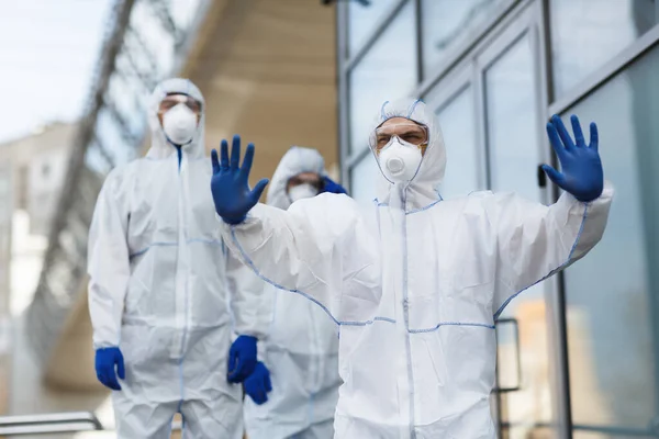 Man in protective hazmat showing warning or stop gesture — Stock Photo, Image