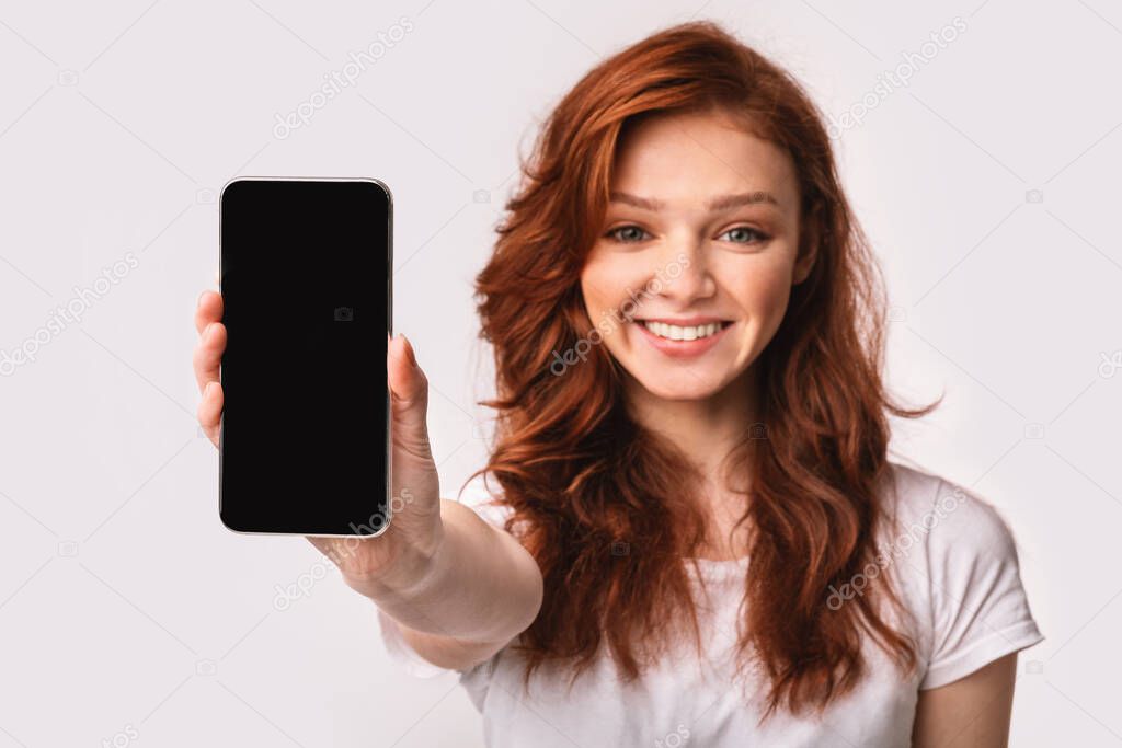 Smiling Girl Showing Cellphone Blank Screen Recommending Application, Studio Shot