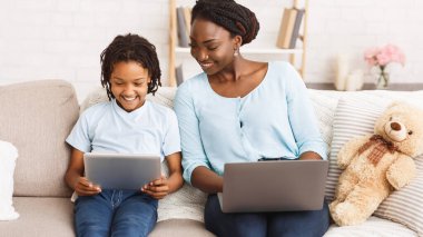 Laptop ve tablet kullanan Afro anne ve kız