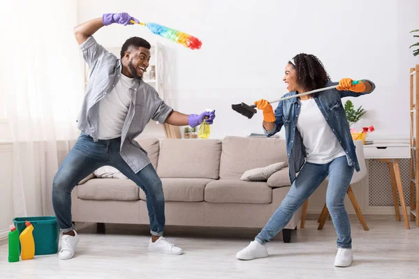 Χαρούμενο μαύρο ζευγάρι που χαζεύει ενώ μαζεύει το διαμέρισμά τους, πολεμώντας παιχνιδιάρικα. — Φωτογραφία Αρχείου