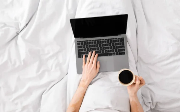 Mujer usando portátil con pantalla en blanco en la cama durante la mañana — Foto de Stock
