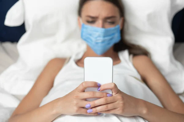 Girl In Mask Using Smartphone Lying In Bed At Home — Stock Photo, Image