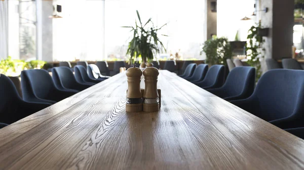 Mesa de madera larga con sal y pimienta, interior del restaurante moderno — Foto de Stock