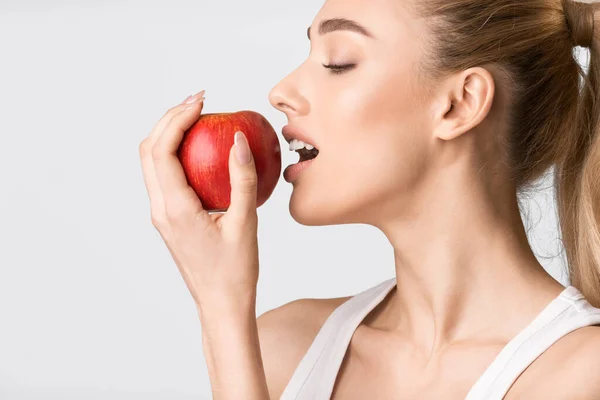 Girl Biting Red Apple Possing On Gray Background, Studio Shot — ストック写真