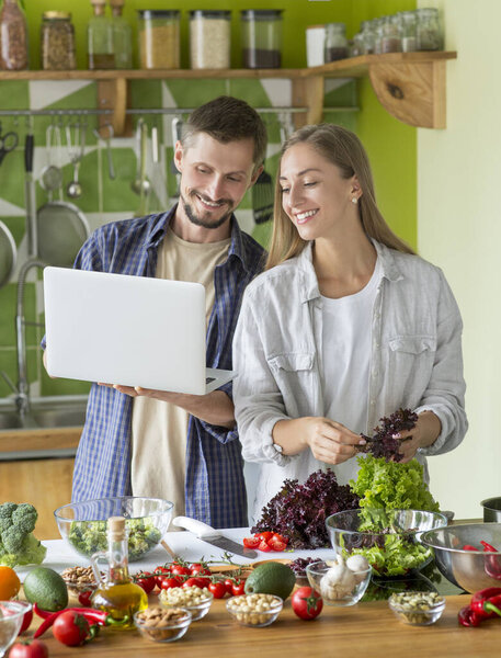 Счастливая вегетарианская пара учится готовить здоровую вегетарианскую еду
