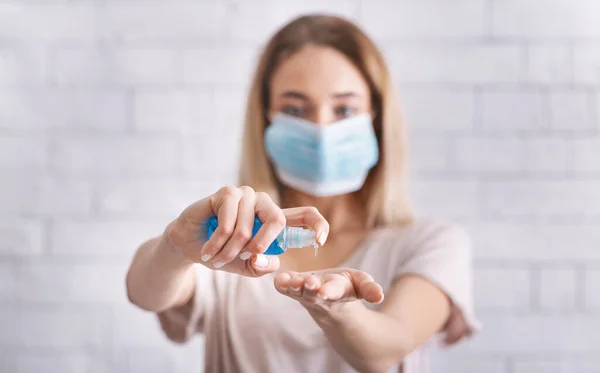 Menina em máscara médica limpa as mãos com anti-séptico — Fotografia de Stock