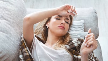 Yüksek ateşi olan kız termometreye bakar.