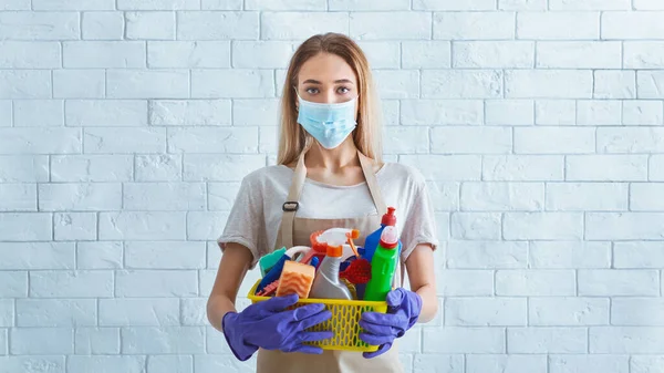Menina em máscara protetora com suprimentos de limpeza — Fotografia de Stock