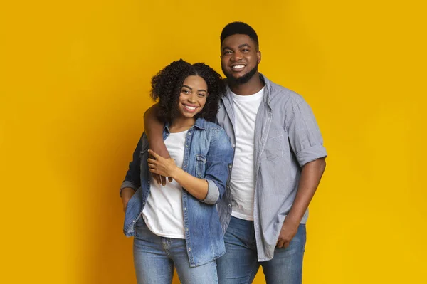 Retrato de feliz pareja negra enamorada posando sobre fondo amarillo — Foto de Stock