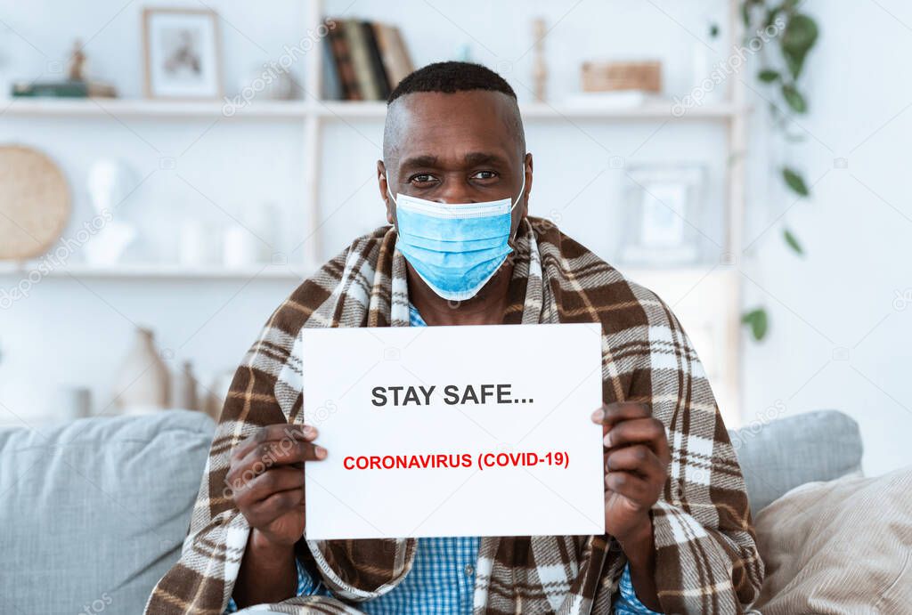 Stay safe during virus outbreak. Senior African American man holding paper sheet with anti-coronavirus text indoors