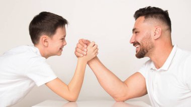 Oyuncu baba ve oğul bilek güreşinde yarışıyorlar.