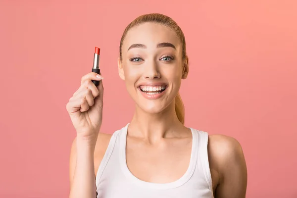 Spännande flicka innehav läppstift leende Posing över rosa bakgrund — Stockfoto
