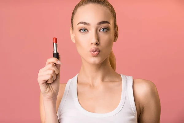 Blond kvinna som håller läppstift Pouting Lips stående i studio — Stockfoto