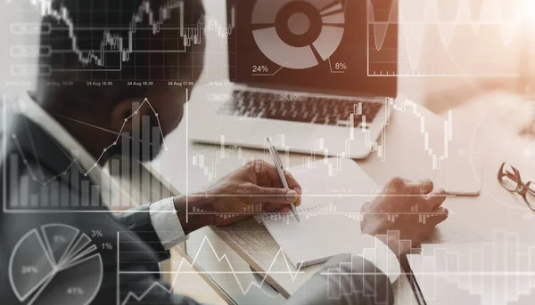 Homme d'affaires afro-américain avec ordinateur portable travaillant au bureau, collage avec des données financières sur écran imaginaire — Photo