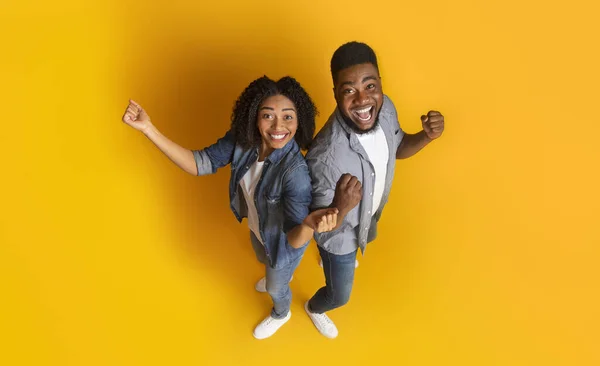 Afrikanskt par glädjande framgång, firar seger med upphöjda nävar, ovan utsikt — Stockfoto