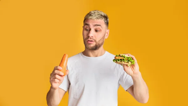 Homem ridículo escolhe legumes ou fast food — Fotografia de Stock