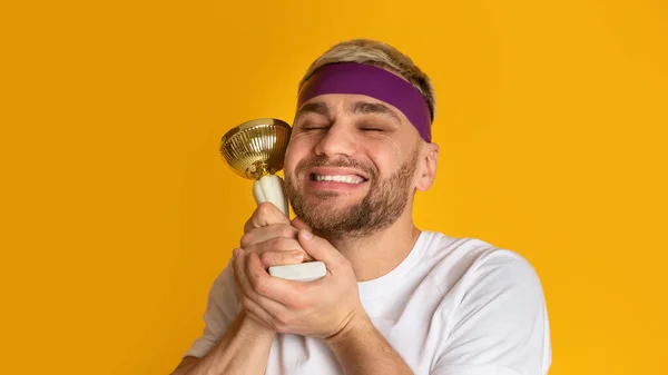 Feliz vencedor pressiona copo de prêmio para si mesmo — Fotografia de Stock