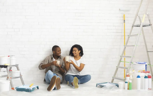 Ζευγάρι κάθεται σε εσωτερικούς χώρους σε νέο διαμέρισμα με εργαλεία ζωγραφικής — Φωτογραφία Αρχείου