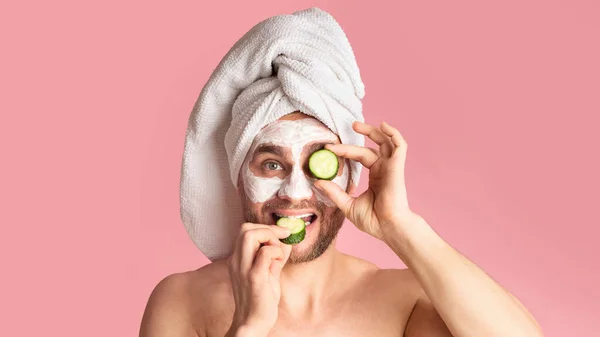 Millennial uomo rende maschera viso e mangia cetriolo — Foto Stock