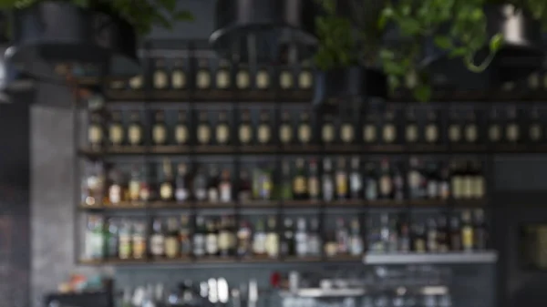 Blurred bar counter with alcohol drinks on shelves, panorama