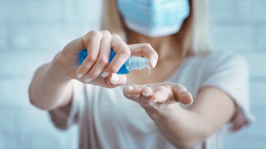 El dezenfeksiyonu. Tıbbi maskeli kadın ellerini temizliyor.