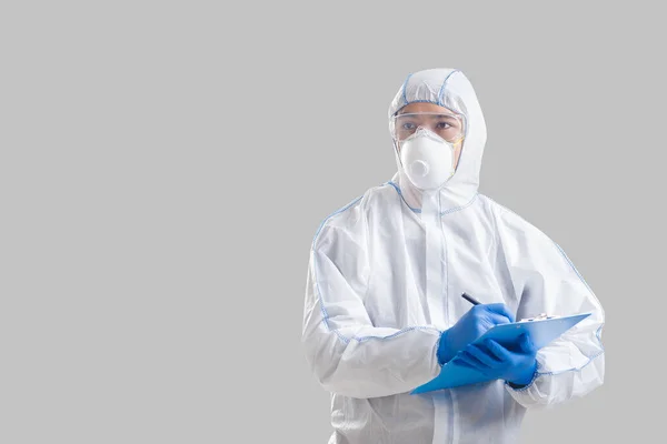 보호용 양복을 입은 아시아 남자가 코로나 바이러스에 대한 자료를 쓴다 — 스톡 사진