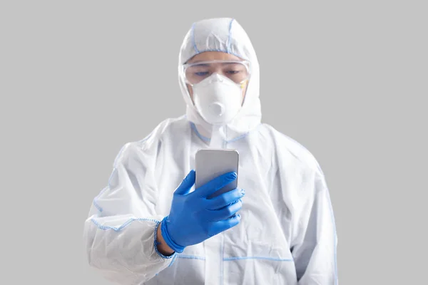 Disinfektor melihat pada isolasi smartphone pada latar belakang abu-abu — Stok Foto
