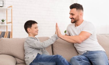 Baba ve oğul evde beşlik çakıyor.