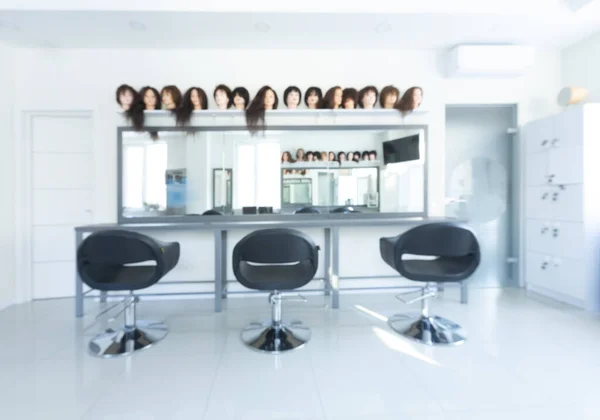 Blurry barber shop interior with wigs on mannequins — Stock Photo, Image