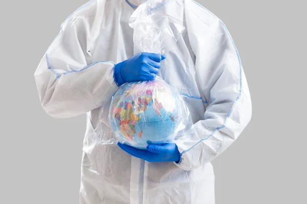 Un danger épidémique mondial. Homme en combinaison de protection tient globe dans un sac en toile huilée — Photo