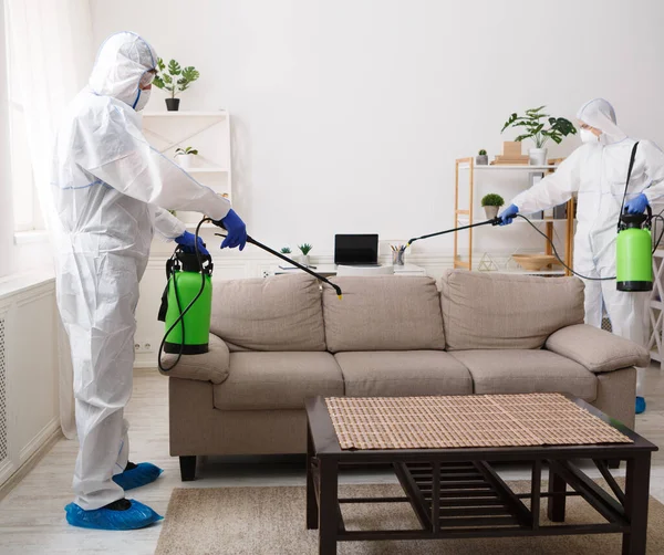 Работники в защитных костюмах дезинфицируют химикатами вашу квартиру — стоковое фото