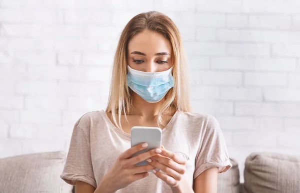 Meisje leest nieuws op smartphone over coronavirus in quarantaine — Stockfoto