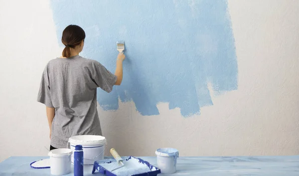 Mujer pintando pared interior con rodillo de pintura en casa nueva — Foto de Stock