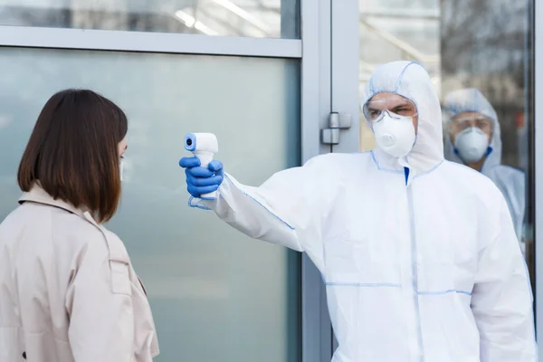 Medisch medewerker in virusbeschermingspak meettemperatuur — Stockfoto