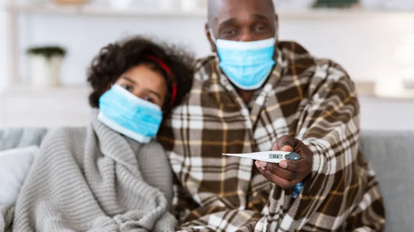 Brote de infección. Familia afroamericana enferma con máscaras protectoras, enfoque en el termómetro en la mano de los abuelos —  Fotos de Stock