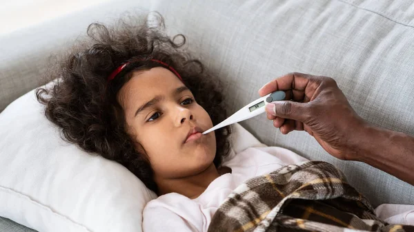 Pandemia mundial. Niña enferma con fiebre alta y su abuelo sosteniendo termómetro en el interior. Panorama —  Fotos de Stock