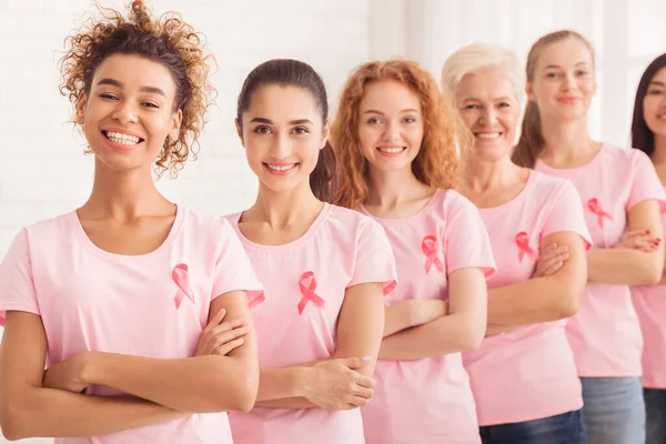 Mujeres multiraciales con cintas rosadas en fila, fondo blanco — Foto de Stock