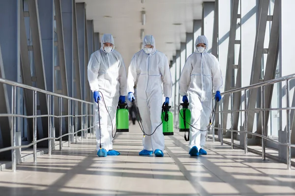 Mensen in beschermende hazmat pakken die vaten dragen — Stockfoto